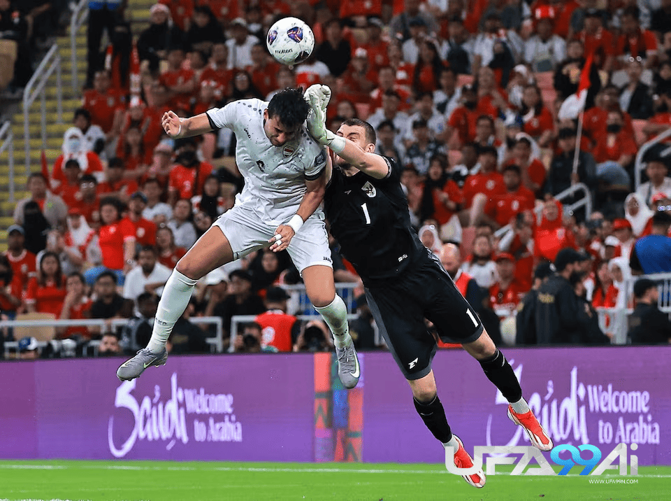 นักเตะทีมชาติอิรักกระโดดโหม่งบอลชนกับผู้รักษาประตูทีมชาติไทยกลางอากาศ ระหว่างการแข่งขันฟุตบอลโลก รอบคัดเลือก ท่ามกลางแฟนบอลเต็มสนาม โดยมีป้าย “Welcome to Arabia” อยู่ด้านหลัง ภาพของ ufa99ai